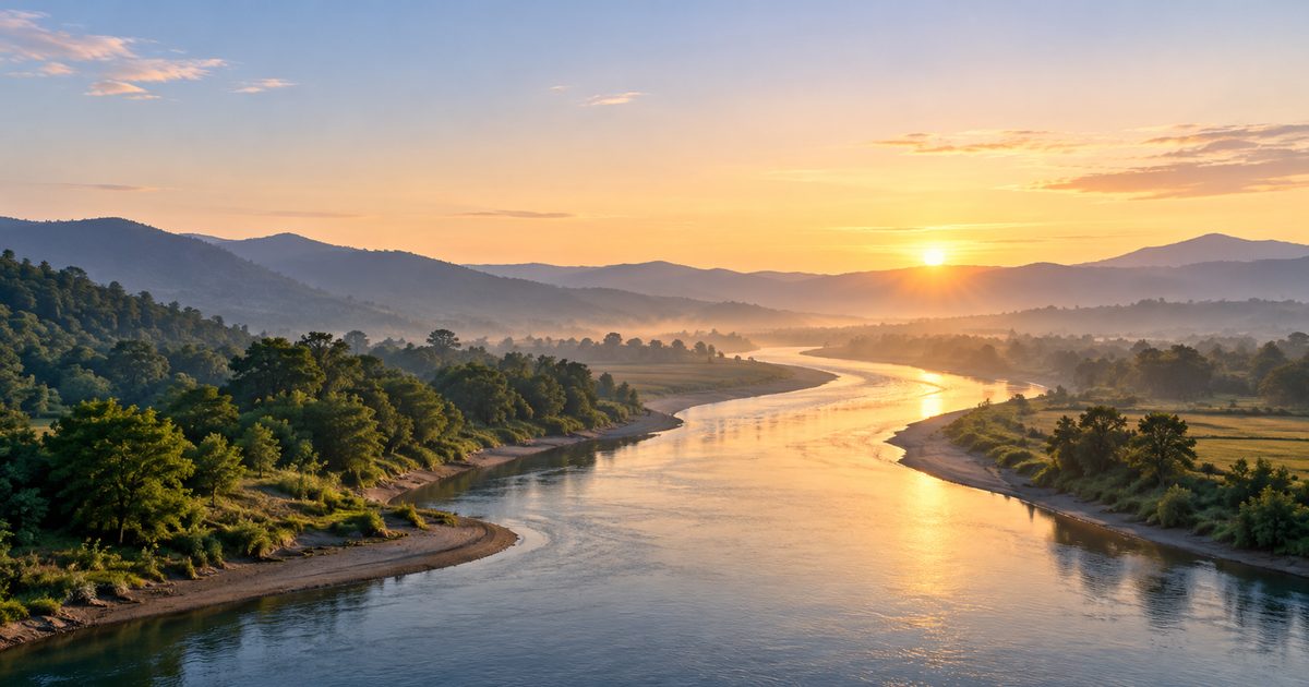 A calm river flowing between its banks at sunrise